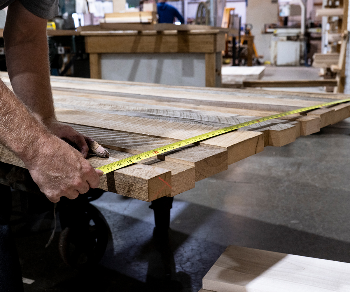 Amish craftsmanship shown through careful wood measuring in a furniture workshop